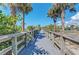 Picturesque wooden boardwalk framed by swaying palm trees, leading toward a beach pavilion at 1183 Cedar Ave, Englewood, FL 34223