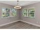 Bright dining area featuring gray wood floors, a modern light fixture, and large windows at 1183 Cedar Ave, Englewood, FL 34223