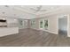 Open-concept living area with gray wood floors, tray ceiling, and a view of the kitchen at 1183 Cedar Ave, Englewood, FL 34223