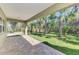 Covered patio overlooking a private backyard with lush landscaping and mature palm trees at 1183 Cedar Ave, Englewood, FL 34223