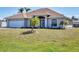 A well-maintained home showcases a manicured lawn and arched doorway, complemented by palm trees and a two car garage at 1317 Le Pera Rd, Englewood, FL 34223