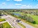 Aerial view of the gated community featuring a golf course, lake and tropical trees at 14026 Royal Pointe Dr, Port Charlotte, FL 33953