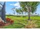 The beautiful backyard features a well-maintained lawn, mature trees, colorful landscaping, and water views at 14026 Royal Pointe Dr, Port Charlotte, FL 33953