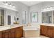The main bathroom boasts a double sink vanity, soaking tub, and glass block window for natural light at 14026 Royal Pointe Dr, Port Charlotte, FL 33953