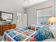 A bright bedroom with two twin beds, ceiling fan, neutral walls, and view to an ensuite bathroom at 14026 Royal Pointe Dr, Port Charlotte, FL 33953