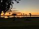 Scenic lake view at sunset showcasing silhouetted palm trees and vibrant colors at 14026 Royal Pointe Dr, Port Charlotte, FL 33953