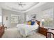 Bright main bedroom boasts tray ceilings, a ceiling fan, neutral walls and carpet, and lots of natural light through several windows at 14026 Royal Pointe Dr, Port Charlotte, FL 33953