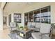 Covered patio area with comfortable seating, ceiling fan, and sliding glass doors with lake views at 14026 Royal Pointe Dr, Port Charlotte, FL 33953
