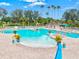 Inviting community pool with ample lounge chairs, and tropical landscaping at 14026 Royal Pointe Dr, Port Charlotte, FL 33953