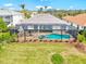 Aerial view of the rear of the property with a screened pool, lanai, and manicured lawn, showcasing the outdoor living space at 14026 Royal Pointe Dr, Port Charlotte, FL 33953