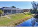Backyard featuring a screened-in pool, lush landscaping, and canal views for relaxation at 14157 Kewanee Ln, Port Charlotte, FL 33981