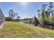 A tranquil backyard with a lush lawn, a canal view, and natural landscaping at 14157 Kewanee Ln, Port Charlotte, FL 33981