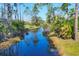 Scenic view of a tranquil canal surrounded by lush greenery and mature trees at 14157 Kewanee Ln, Port Charlotte, FL 33981