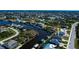Expansive aerial perspective of waterfront homes lining canals, nestled within a verdant, tree-filled neighborhood reaching afar at 14718 San Domingo Blvd, Port Charlotte, FL 33981