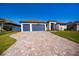 Stunning exterior showcasing a home with a blue three-car garage and beautiful paver driveway at 14718 San Domingo Blvd, Port Charlotte, FL 33981