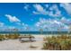 Serene beach view with clear blue sky, white sand, grassy dunes, and a weathered picnic table at 15044 Acorn Cir, Port Charlotte, FL 33981