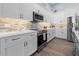 Modern kitchen with white cabinets, stainless steel appliances, and stylish backsplash at 15044 Acorn Cir, Port Charlotte, FL 33981