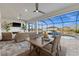 Covered lanai features a dining area and lounge area with a stunning view of the water and pool at 15044 Acorn Cir, Port Charlotte, FL 33981