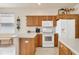 Classic kitchen with wood cabinets, white appliances, and a window providing natural light at 16 Windward Ter, Placida, FL 33946
