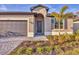 Charming single-story home with a gray garage door, walkway, and beautiful front yard landscaping at 1602 Saddlewood Cir, Port Charlotte, FL 33953