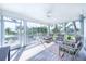 Relaxing screened porch with tropical furniture offering a peaceful view of the surrounding palm trees at 16250 Sunset Pines Cir, Boca Grande, FL 33921
