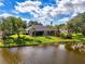 A beautiful backyard is captured from the lake featuring a covered lanai surrounded by palm trees and a well-manicured lawn at 17 Dominica Dr, Englewood, FL 34223