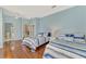 Bedroom featuring two twin beds, a ceiling fan, wood floors, and bright blue walls at 17 Dominica Dr, Englewood, FL 34223