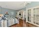 Bright bedroom featuring two twin beds, a ceiling fan, wood floors, and bright blue walls at 17 Dominica Dr, Englewood, FL 34223