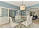 Bright dining room with blue walls, white chairs, and modern chandelier with view of the outdoor pool at 17 Dominica Dr, Englewood, FL 34223