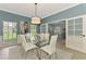 Bright dining room with blue walls, white chairs, and modern chandelier with view of the Gathering room at 17 Dominica Dr, Englewood, FL 34223
