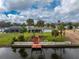 View of home's backyard with a canal, dock, palm trees, and green lawn at 184 Eppinger Dr, Port Charlotte, FL 33953