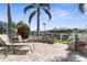 Backyard waterfront seating area on a brick patio with lush landscaping and a view of the canal at 2160 Palm Tree Dr, Punta Gorda, FL 33950