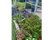 Lush, colorful flowers and greenery are neatly arranged in a garden bed by a screened lanai at 2160 Palm Tree Dr, Punta Gorda, FL 33950