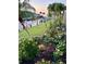 Vibrant and landscaped backyard featuring a canal view, dock, flowering beds, and mature palm trees at 2160 Palm Tree Dr, Punta Gorda, FL 33950