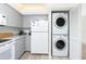 Bright kitchen featuring gray cabinetry, white appliances, and stacked washer/dryer at 2255 N Beach Rd # 13, Englewood, FL 34223