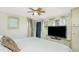 Bedroom featuring a white bed, ceiling fan and TV set. Windows dressed with light, floral curtains provide natural light at 3210 Holly Ave, Englewood, FL 34224