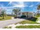 Charming mobile home featuring an extended driveway, covered porch, and well-maintained lawn, offering comfortable living at 3210 Holly Ave, Englewood, FL 34224