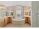 Luxurious bathroom featuring a soaking tub, dual sinks, vanities, and a glass-enclosed shower at 4050 Rock Creek Dr, Port Charlotte, FL 33948