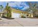 Bright yellow home featuring an attached garage and lush, tropical landscaping at 4050 Rock Creek Dr, Port Charlotte, FL 33948