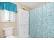 Bright bathroom featuring a cabinet, toilet, window, and shower curtain at 414 Circlewood Dr # H2, Venice, FL 34293