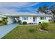 Charming single-story home with vibrant blue shutters, white exterior, and lush landscaping for curb appeal at 414 Circlewood Dr # H2, Venice, FL 34293