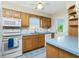 Cozy kitchen with wood cabinets, white appliances, and a window overlooking the outdoors at 414 Circlewood Dr # H2, Venice, FL 34293