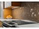 Modern kitchen detail featuring a glass backsplash, stainless steel cooktop, and quartz countertop at 425 Nassau S St, Venice, FL 34285