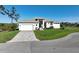 Lovely home with a two-car garage, brick driveway, mature trees, and lush green lawn at 5 Reef Ct, Placida, FL 33946