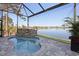 Screened-in pool with a relaxing rock waterfall feature and tranquil lake view at 5 Reef Ct, Placida, FL 33946