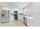 Bright kitchen with stainless steel appliances, white cabinets, and a stylish blue backsplash at 613 Chestnut Ln, Englewood, FL 34223