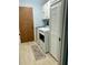 Well-lit laundry room features white washer, dryer, cabinets, and a door to the outside at 613 Chestnut Ln, Englewood, FL 34223