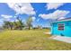 Bright blue home exterior with a spacious backyard and healthy lawn under a partly cloudy sky at 6264 Drucker Cir, Port Charlotte, FL 33981