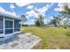 Expansive backyard featuring a screened lanai and a large, well-maintained lawn under a partly cloudy sky at 6264 Drucker Cir, Port Charlotte, FL 33981