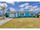 Charming turquoise home featuring a white garage door, front door, white trimmed windows, and a manicured front lawn at 6264 Drucker Cir, Port Charlotte, FL 33981
